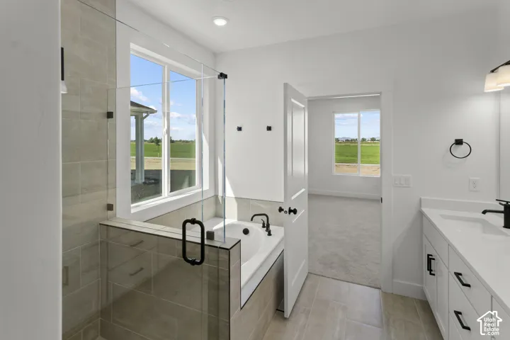 Walk-in shower with clear glass enclosure and tile surround, freestanding soaking tub, dual vanity with undermount sinks, and ample natural light from multiple windows