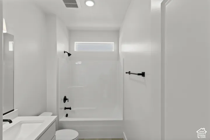 Bathroom featuring a vanity with an integrated sink, black fixtures, and a shower-tub combination