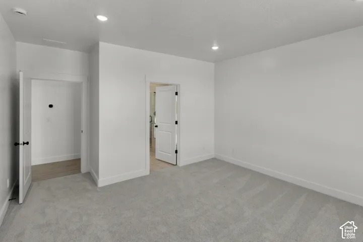 Neutral wall tones with recessed lighting, light-toned carpet, and solid core doors with black hardware