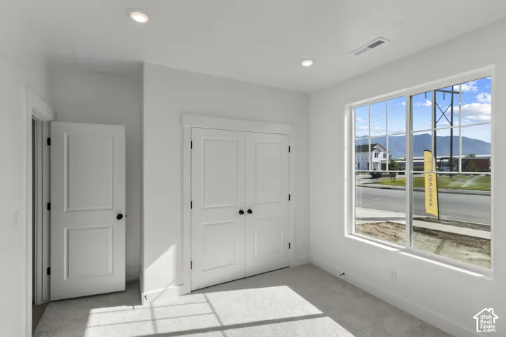 Recessed ceiling lighting, white paneled doors, and a large window with grid panes