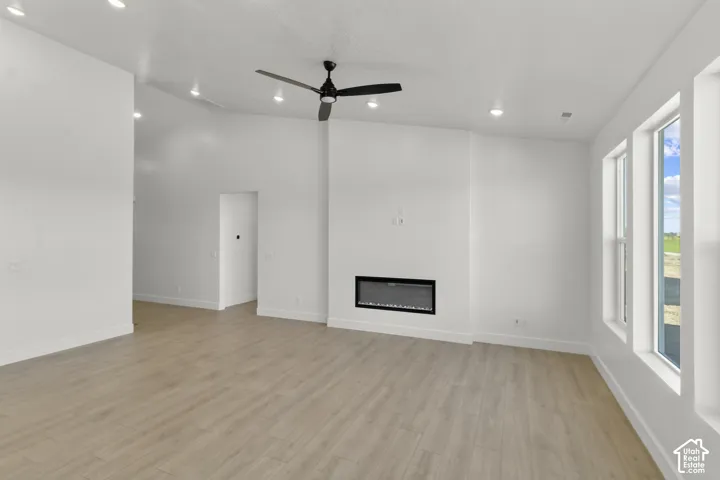 Spacious living area featuring wood-finish flooring, a contemporary electric fireplace, and a ceiling fan
