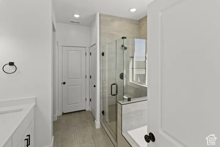 Glass-enclosed shower with a built-in bench, tiled walls, and a matte black shower head