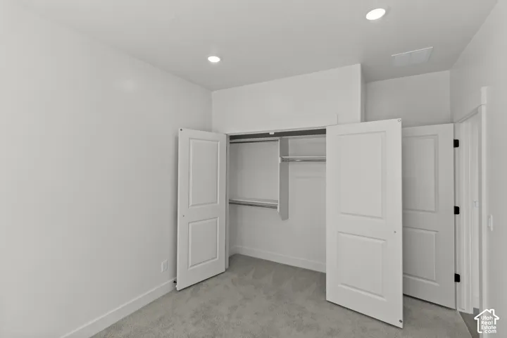 Wall-to-wall carpeting, recessed ceiling lighting, and a bi-fold closet with shelving and hanging rods