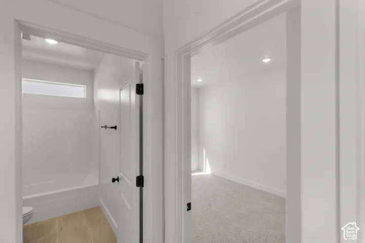 Recessed lighting, wood-finish flooring, white walls, white trim, and white doors