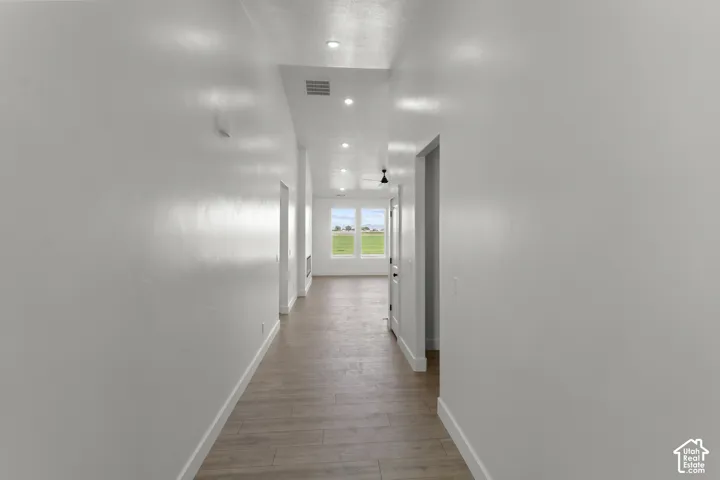 Recessed lighting illuminates wood-finish flooring in this hallway