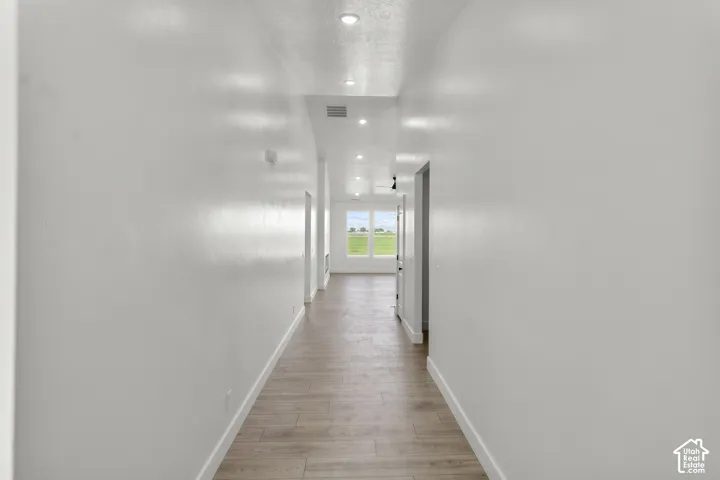 Recessed lighting, wood-finish flooring, white trim, and white walls