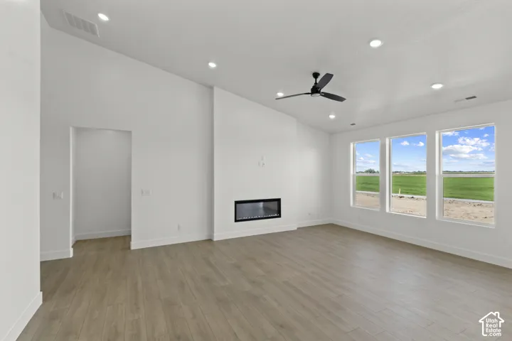 Vaulted ceiling, wood-finish flooring, recessed lighting, linear fireplace, and ceiling fan