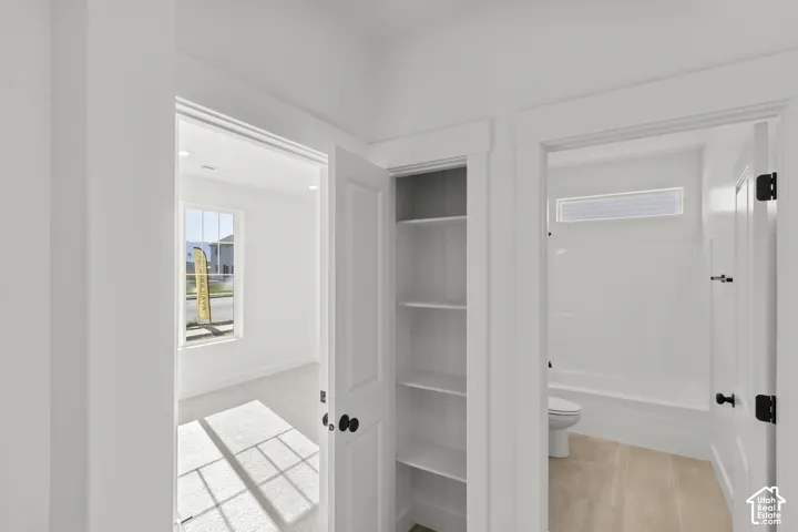 Integrated shelving unit, panel doors with matte black hardware, white wall finishes, and light-toned flooring