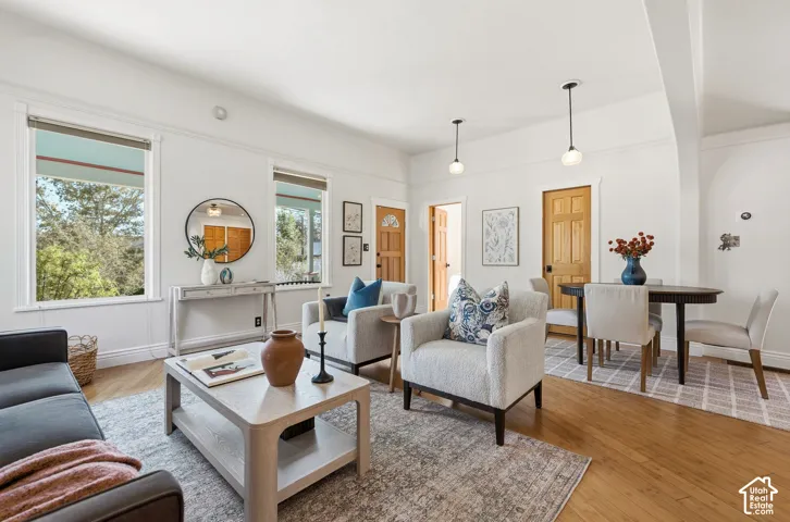 Bright living area , hardwood flooring, freshly painted walls, and pendant lighting fixtures