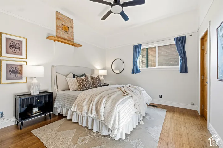 Wood-finish flooring, white walls, ceiling fan, and a wood door with matching trim