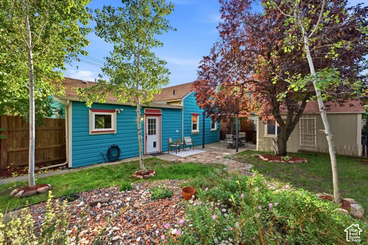 Vibrant exterior siding with contrasting trim, private patio space, mature trees, and a detached outbuilding
