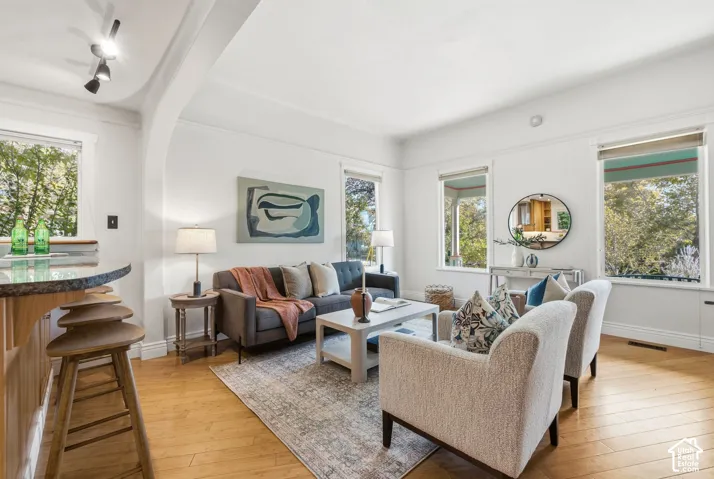 Bright living area , hardwood flooring, freshly painted walls, and pendant lighting fixtures track lighting, and a built-in bar with a granite countertop
