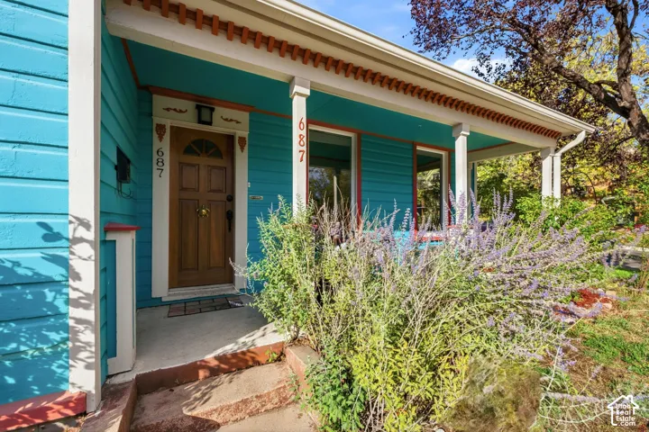 Covered front porch with decorative trim, wood entry door, and concrete steps