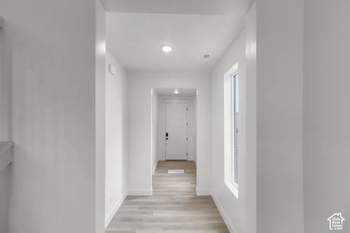 Entryway featuring wood-finish flooring, recessed lighting, white trim, and a white paneled door