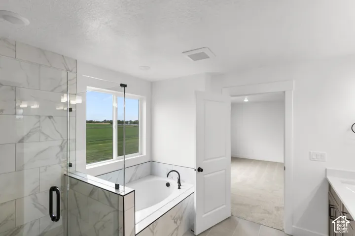 Walk-in shower with clear glass enclosure, a built-in soaking tub, and a window with expansive outdoor scenery