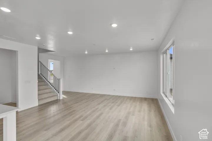 Recessed lighting, light wood-finish flooring, staircase with carpeted treads, and multiple windows
