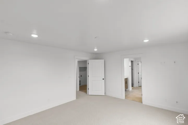 Recessed lighting illuminating a spacious room with light-toned carpeting and white walls