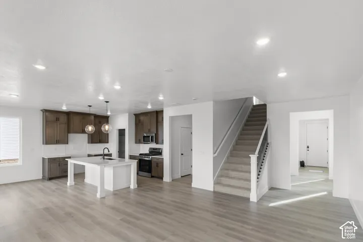 Spacious interior with wood-finish flooring, a kitchen island, dark wood cabinetry, and a carpeted staircase with a white railing
