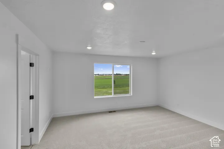 Neutral wall paint, recessed ceiling lighting, light-toned carpet flooring, and a large window