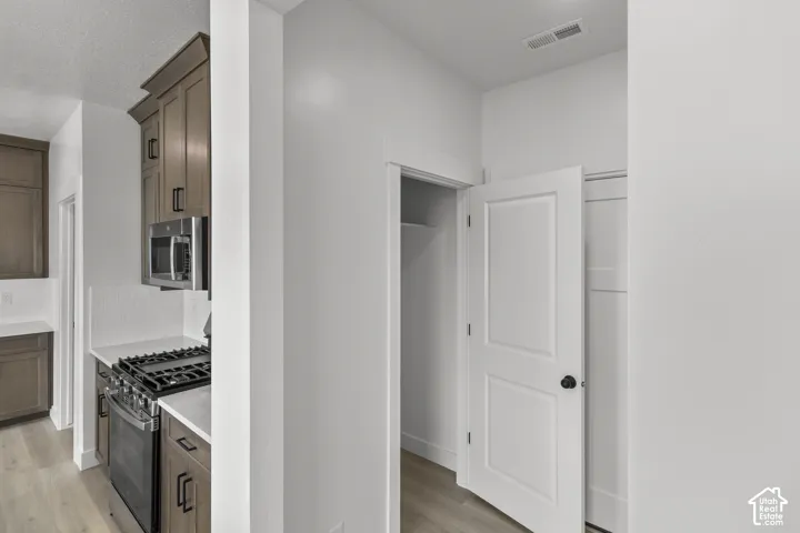 Kitchen featuring wood-finish flooring, stainless steel appliances, and white countertops