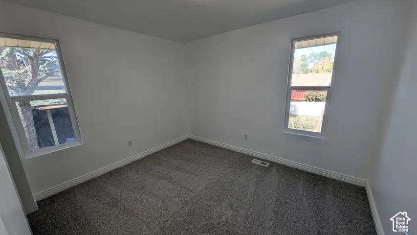 Neutral wall finishes, grey carpet flooring, two rectangular windows, and white trim