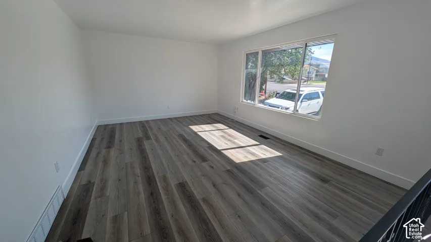 Wood-finish flooring with white baseboards and neutral wall paint
