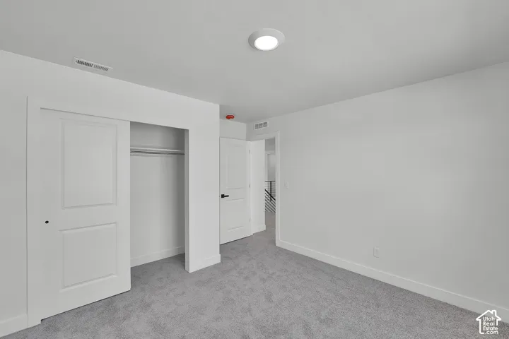 Plush gray carpeting, white walls, white trim, recessed ceiling lighting, and a white sliding closet door with black hardware