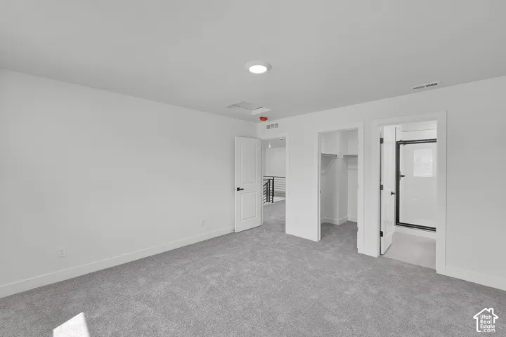 Spacious room featuring gray carpeting, recessed ceiling lighting, and crisp white walls