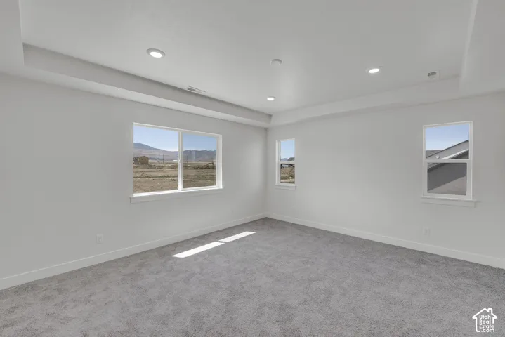Recessed lighting illuminating a spacious room with light gray carpeting and white walls