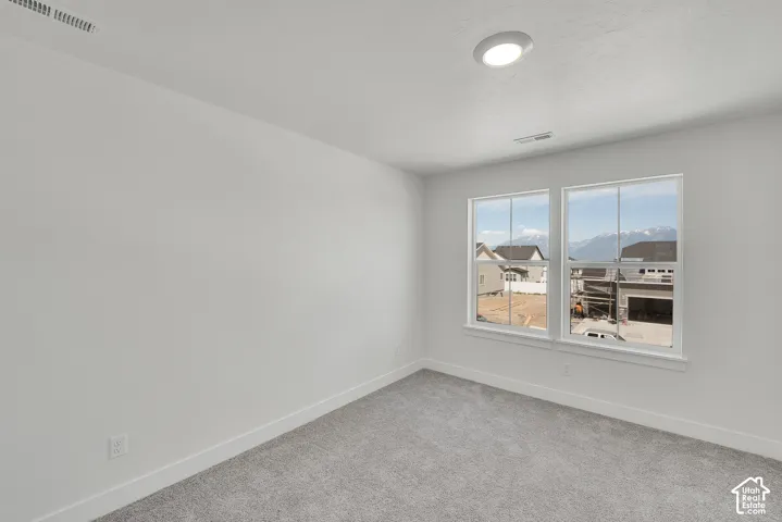 Bright room with two large windows, featuring gray carpeting, white walls, and a ceiling-mounted light fixture
