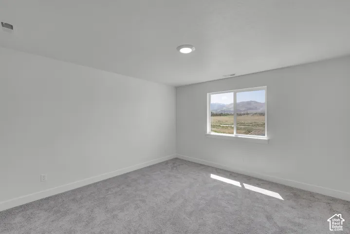 White walls, recessed ceiling lighting, light gray carpeting, and window offering scenic mountain and field backdrop