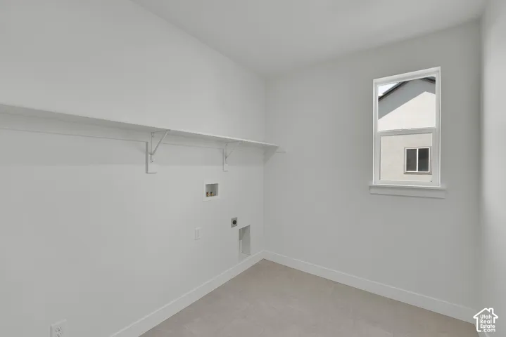 White interior walls with a single window, a built-in shelf, and light-colored tile flooring
