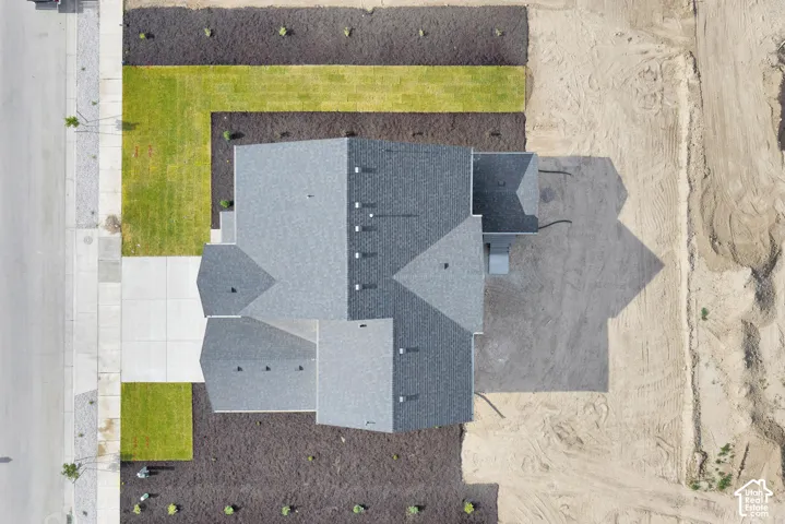 Asphalt shingle roof, concrete driveway, landscaped front yard with grass and mulch, and a large undeveloped rear lot