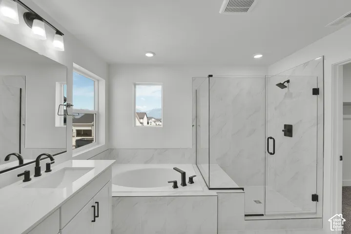 Dual vanity with integrated sinks and black fixtures, a built-in soaking tub, and a glass-enclosed shower with tile surround