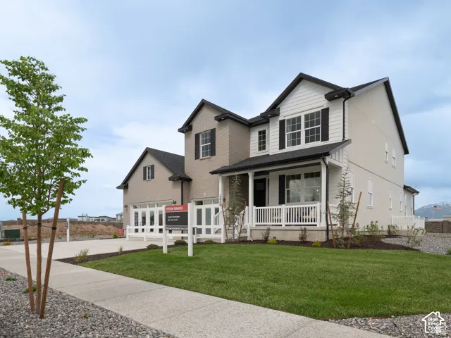 Contemporary exterior featuring a covered porch with white railings, a two-car garage, and a neatly manicured lawn