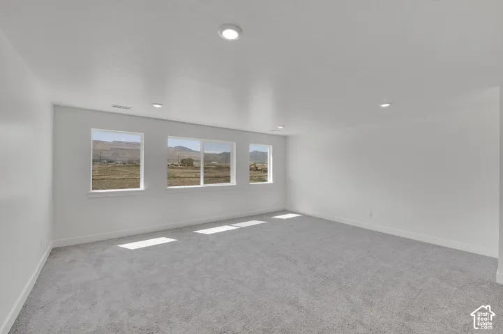 Recessed lighting, light-toned carpeting, white walls, and multiple windows