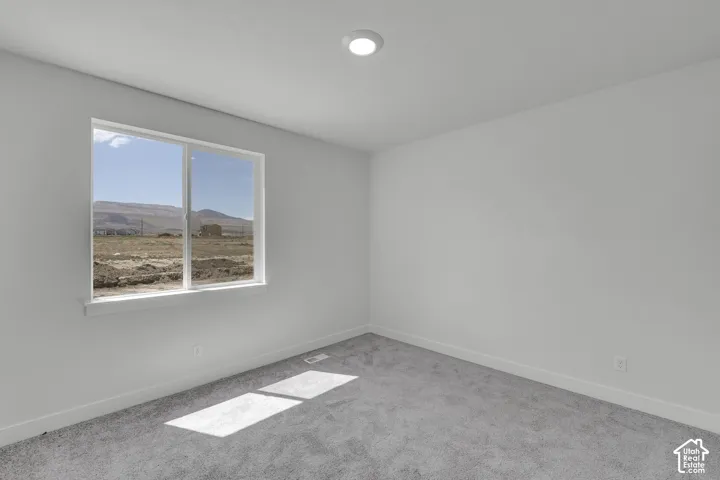 Recessed ceiling light, white painted walls, gray carpeting, white trim, and a window with mountain scenery