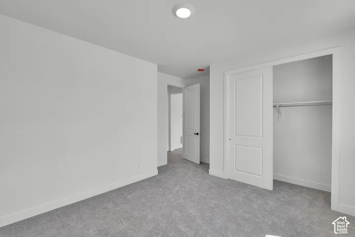 Plush gray carpeting, bright recessed lighting, modern paneled doors, and a functional closet with shelving