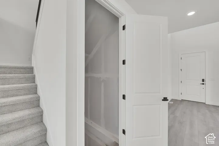 Staircase with carpeted treads, white painted walls, and wood-finish flooring