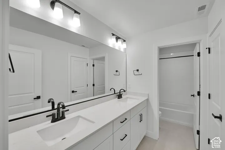 Double vanity with white cabinetry, matte black hardware, and an expansive mirror