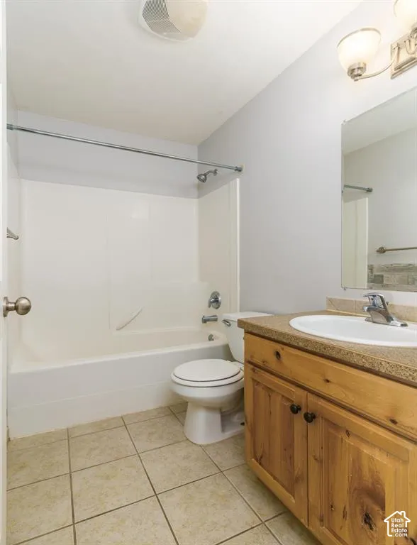 Tub and shower combination, wood-finish vanity with countertop, drop-in sink, and tile flooring
