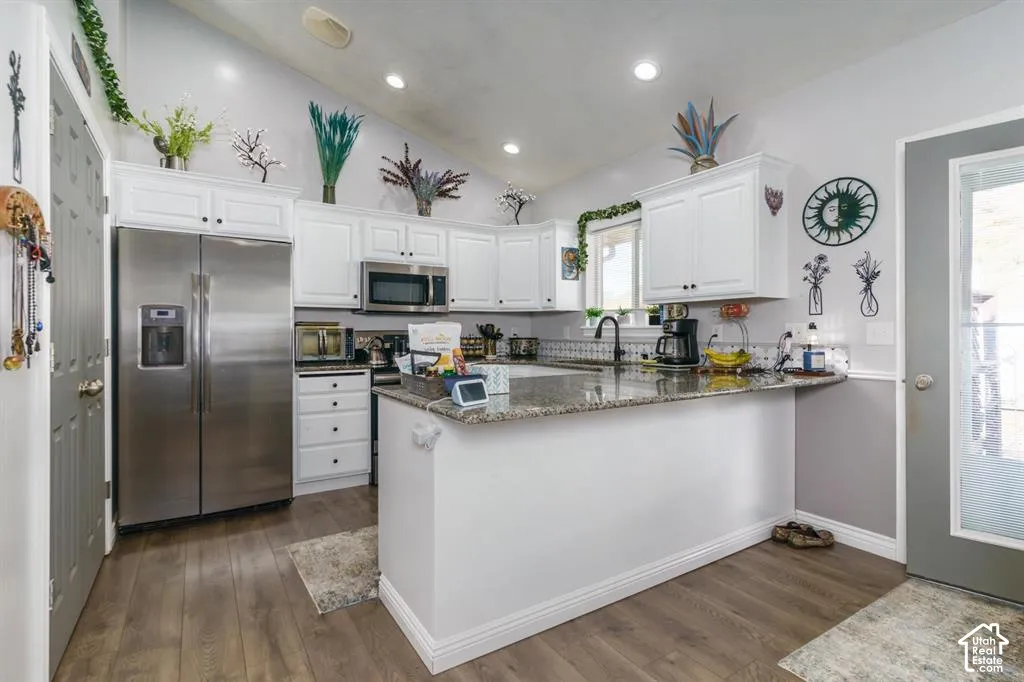 Kitchen featuring white cabinetry, wood-finish flooring, recessed lighting, a stainless steel refrigerator, and granite countertops