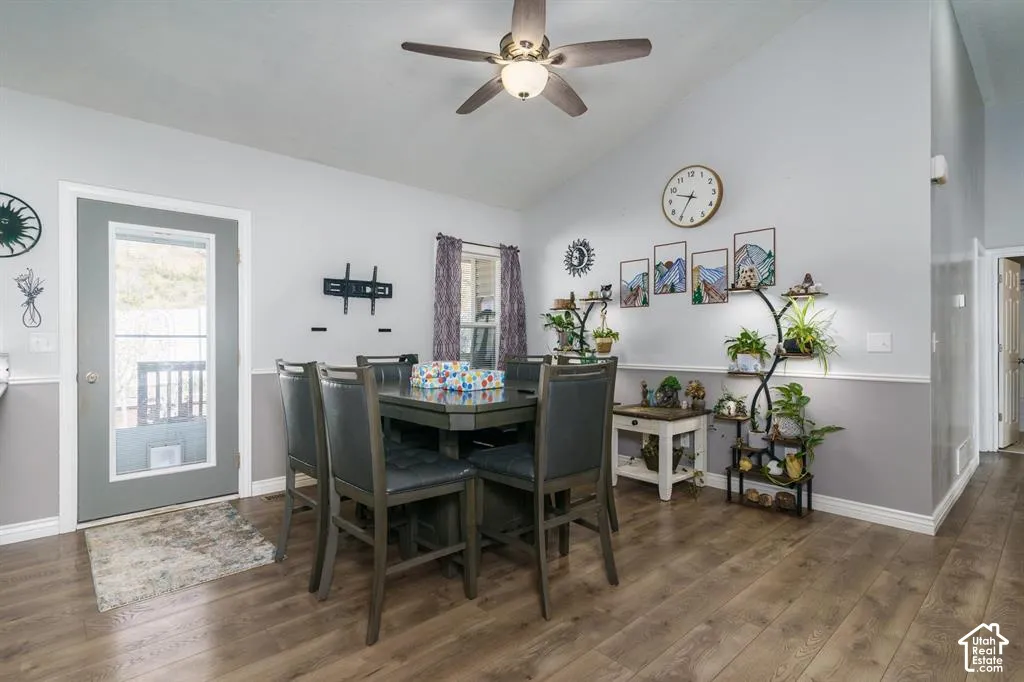 Vaulted ceiling, wood-finish flooring, half-lite door, two-tone wall treatment, and ceiling fan with integrated lighting