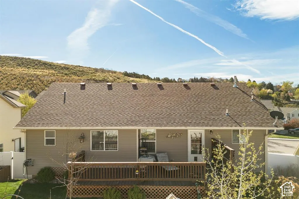 Rear exterior featuring a wood deck, horizontal siding, and a shingled roof