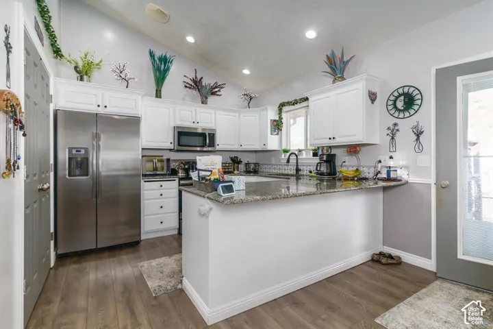 Kitchen featuring white cabinetry, wood-finish flooring, recessed lighting, a stainless steel refrigerator, and granite countertops
