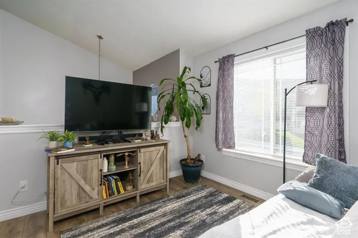 Interior with wood-finish flooring, white trim, and a window with blinds