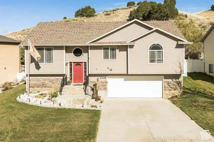 Split-level residence featuring a two-car garage, red front door, and arched window accent