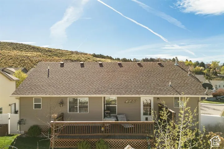 Rear exterior featuring a wood deck, horizontal siding, and a shingled roof
