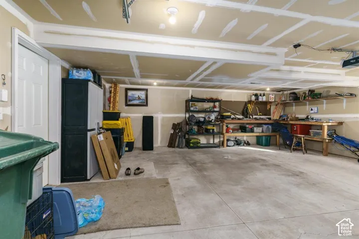 Concrete floor garage with exposed ceiling joists and unfinished drywall walls