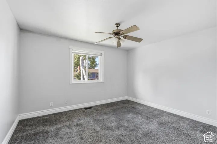 Wall-to-wall carpeting with a bright window, crown molding, and a ceiling fan with integrated lighting